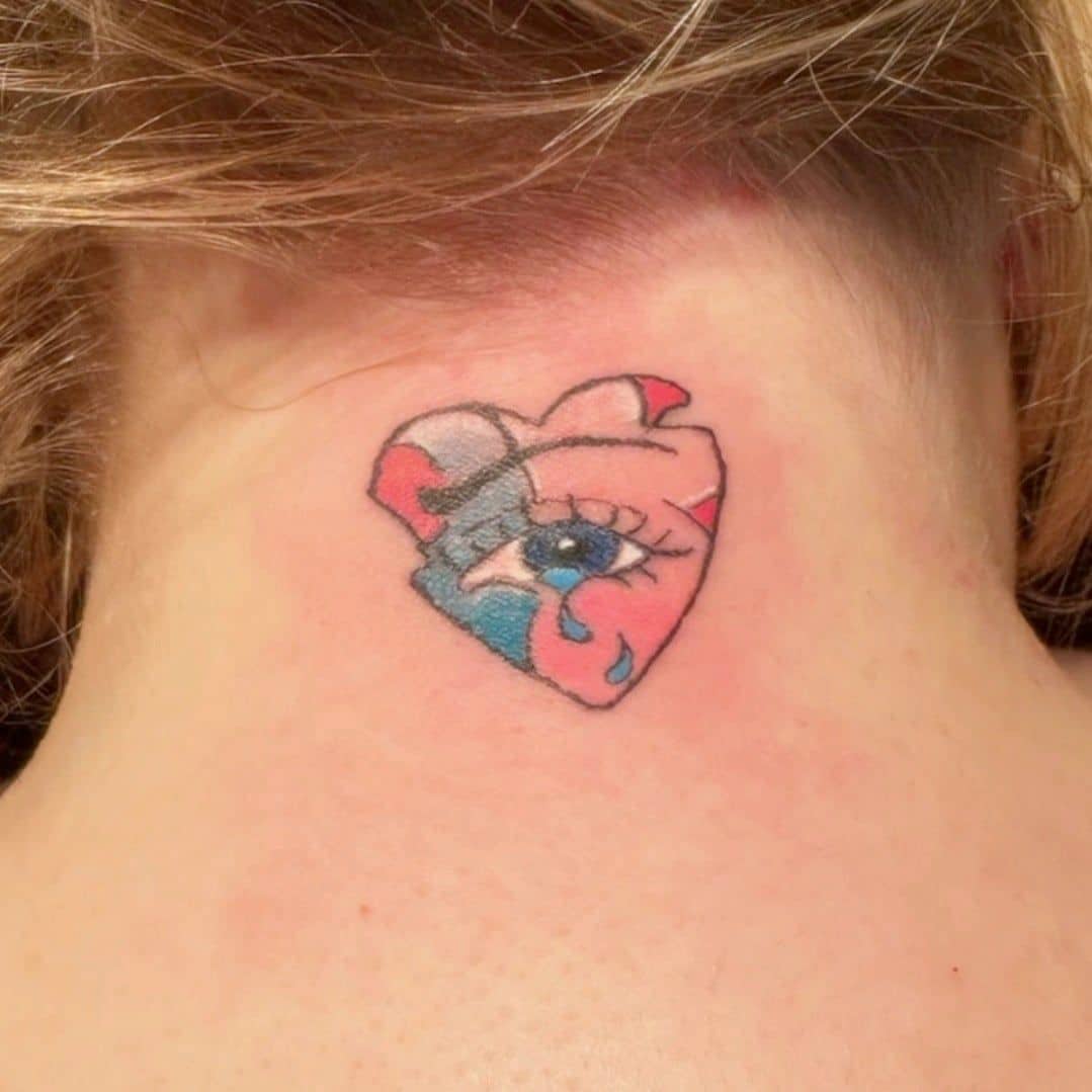 Tattoo by Jake Brewer, heart holding an eye, in colour, on the back of the neck