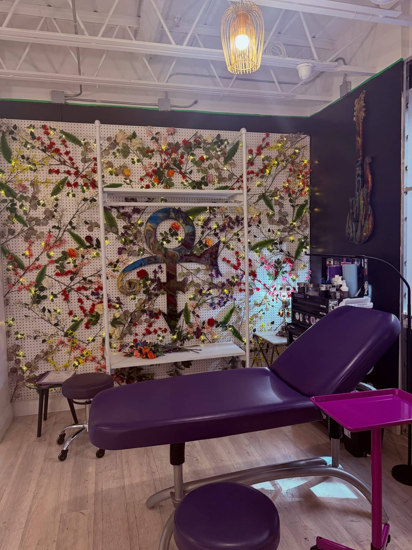 The tattoo chair at Apollonia Ink in front of the floral wall built around the Prince symbol