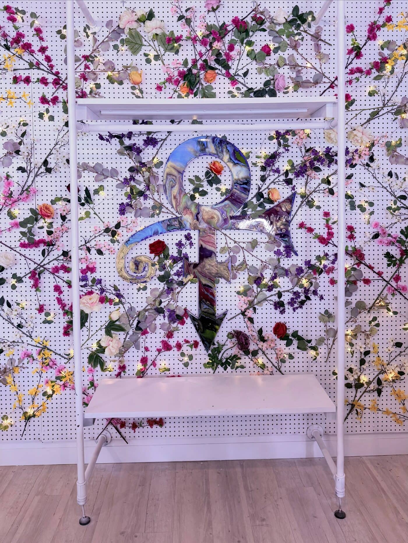 The floral display wall with a mirrored Prince symbol at the centre