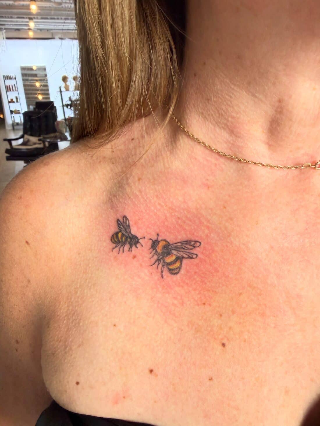 Tattoo by Apollonia Ink in Barrie, two fine line bees across a collarbone