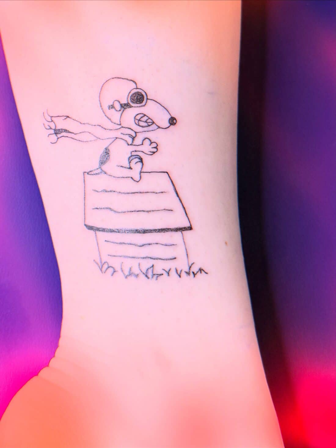 Tattoo by Apollonia Ink in Barrie, fine line Snoopy on his doghouse with script beneath