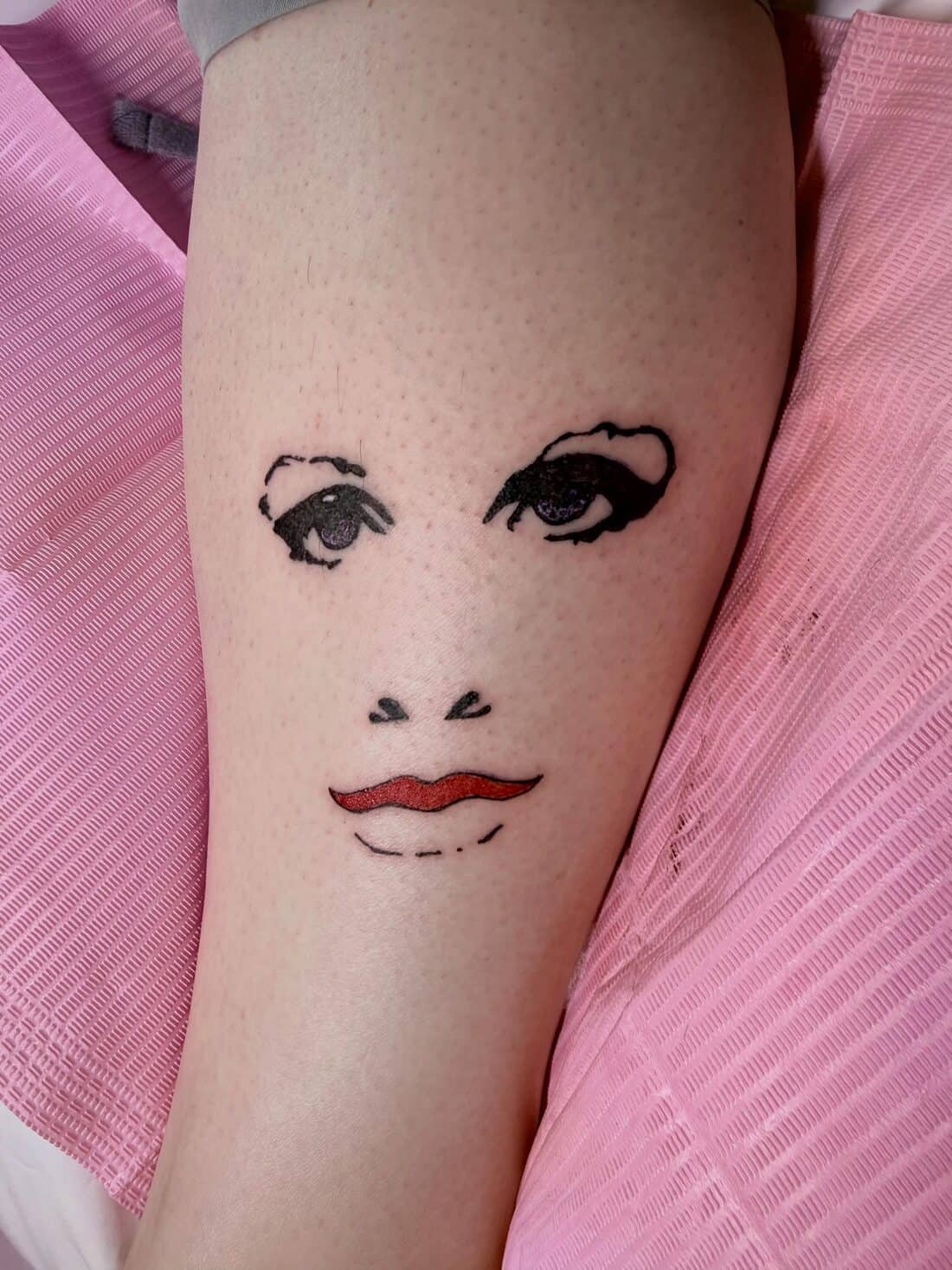 Tattoo by Apollonia Ink in Barrie, fine line face with red lips on a thigh