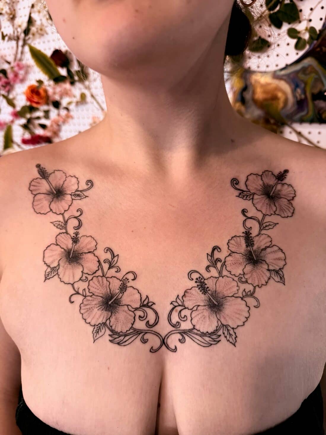 Tattoo by Apollonia Ink in Barrie, fine line floral garland across the collarbones and chest
