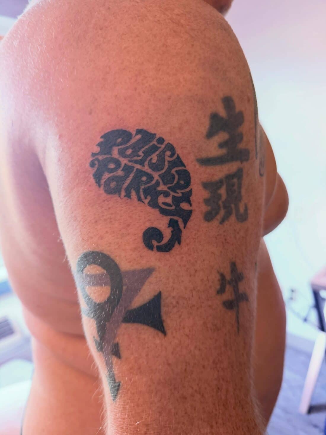 Tattoo by Apollonia Ink in Barrie, Paisley Park lettering with Japanese characters across a shoulder